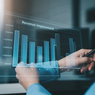 Hands interact with a transparent digital display showing a bar graph titled Revenue Improvement indicating growth over time.